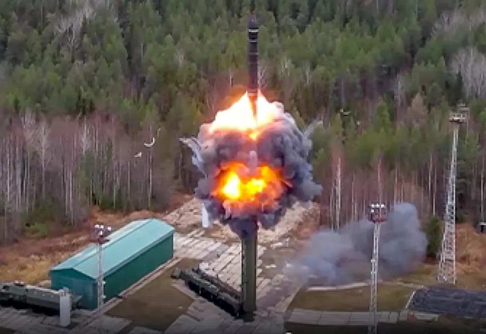 A missile engulfed in smoke and flame launching from a clearing in the woods. 