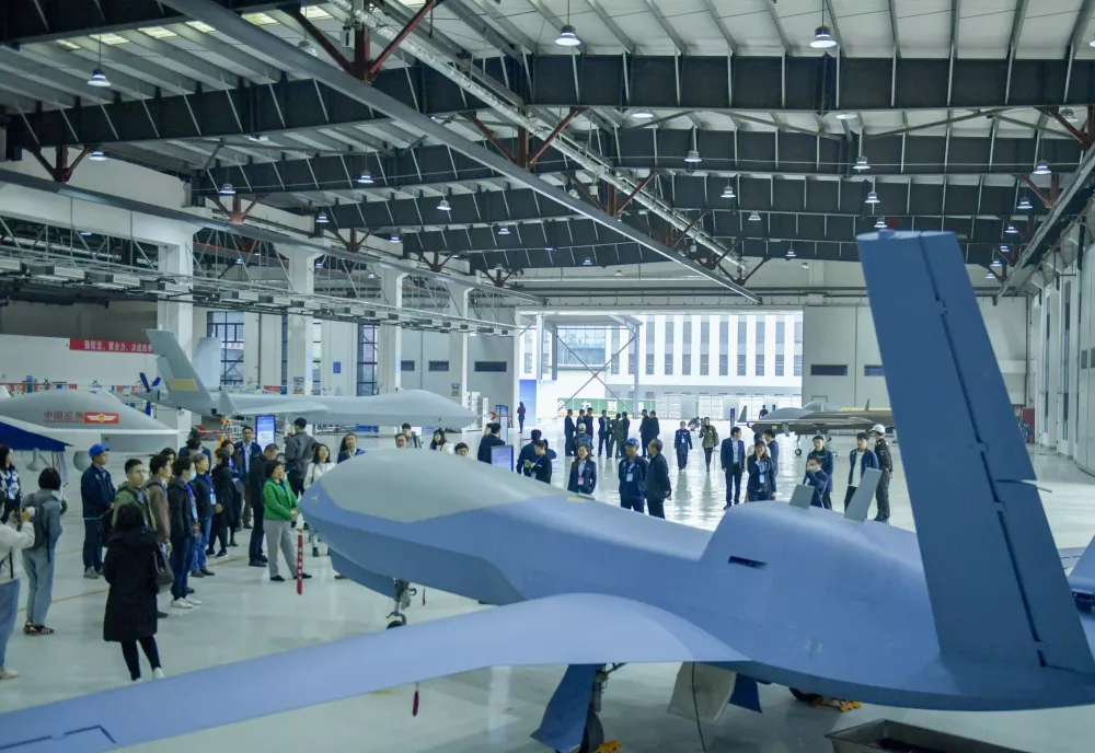 An unmanned aerial vehicle in a hangar surrounded by people.