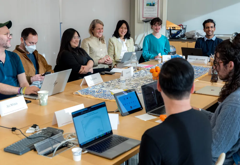 Margaret Williams and a group of Harvard Kennedy School students smile and laugh around a conference table.
