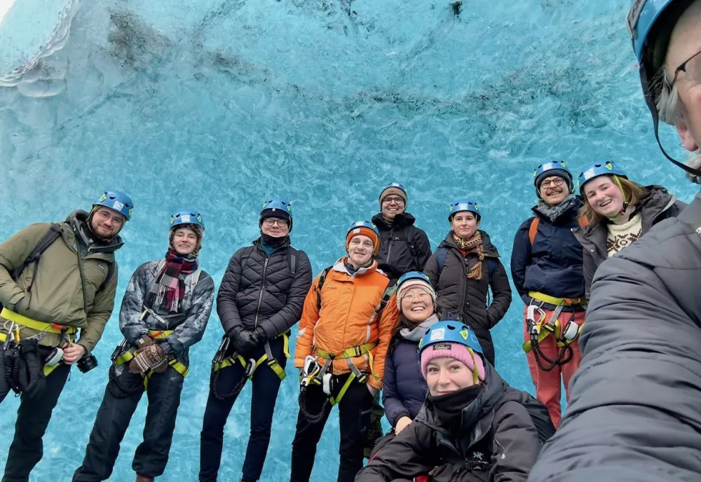 A group of graduate students pose for a selfie while standing on top of a glacier in Iceland.
