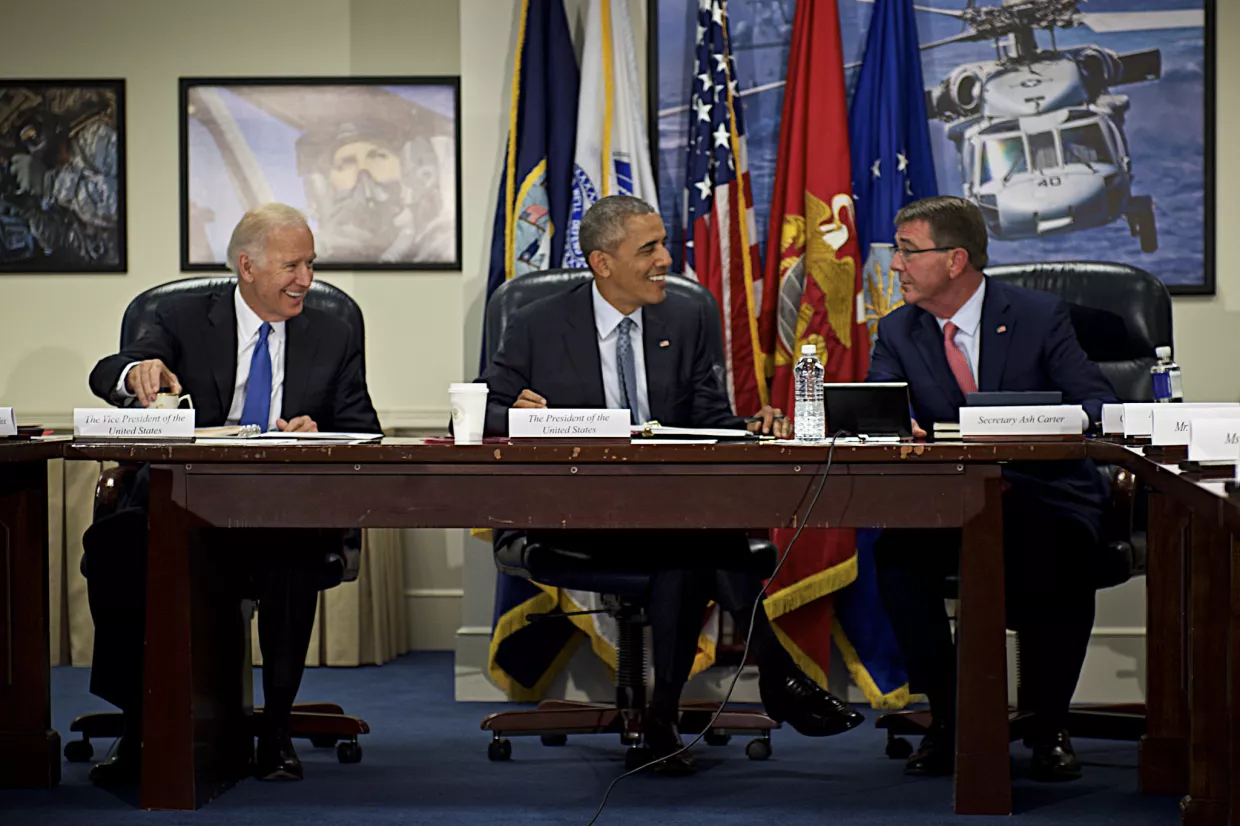 vIce President Biden, President Obama, and Secretary Ash Carter sitting at a table in the Pentagon smiling.