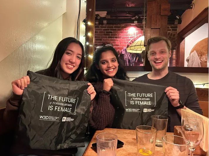 3 people holding shirts that say "the future is female"