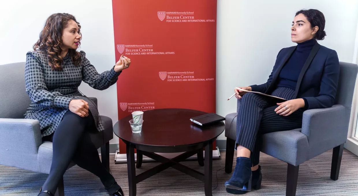 Desirée Cormier Smith at left facing Erika Manouselis at right, both seated on either side of a crimson banner with the Belfer Center word mark.