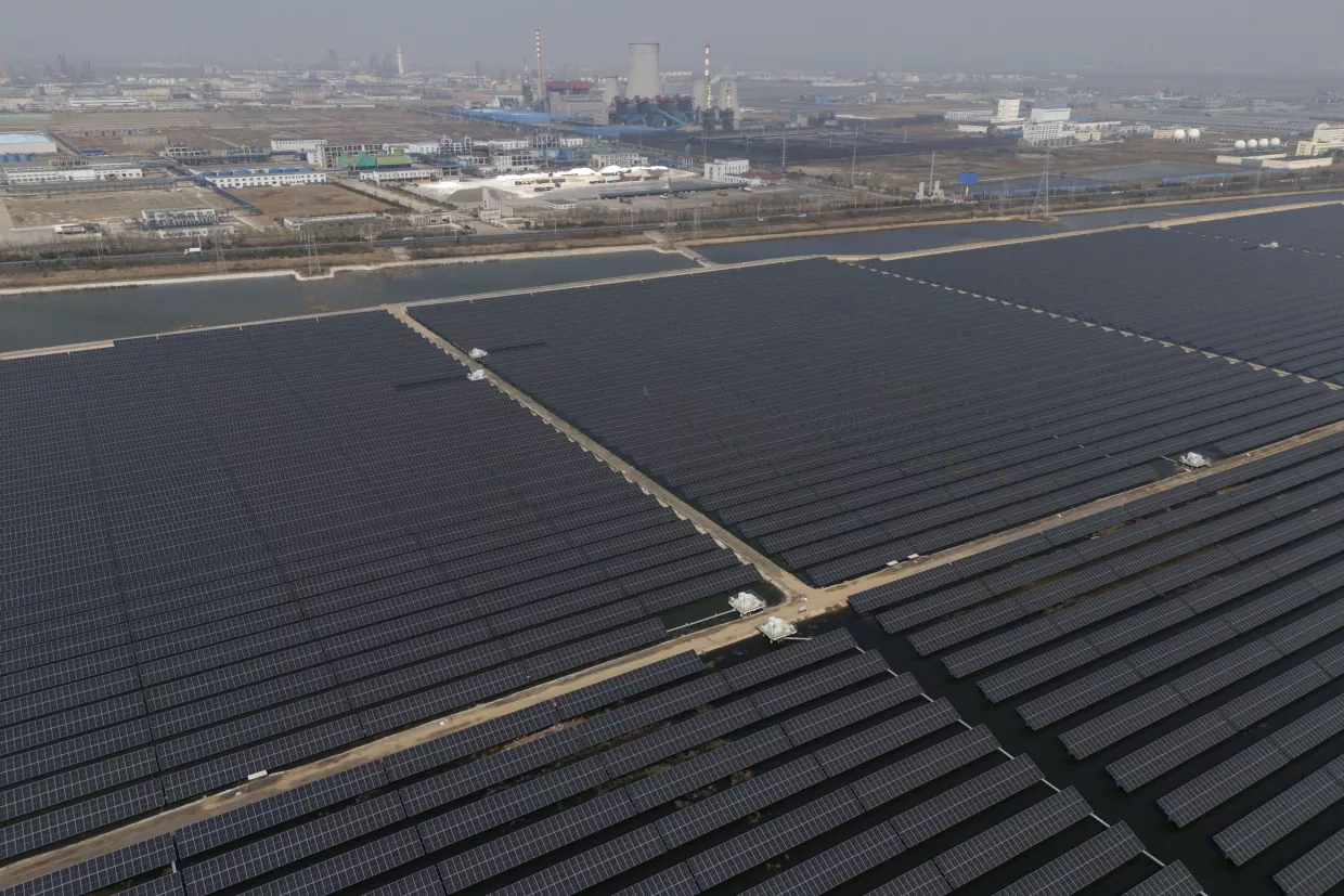 A solar farm operates near a chemical plant on the outskirts of Weifang in eastern China's Shandong province on March 22, 2024.