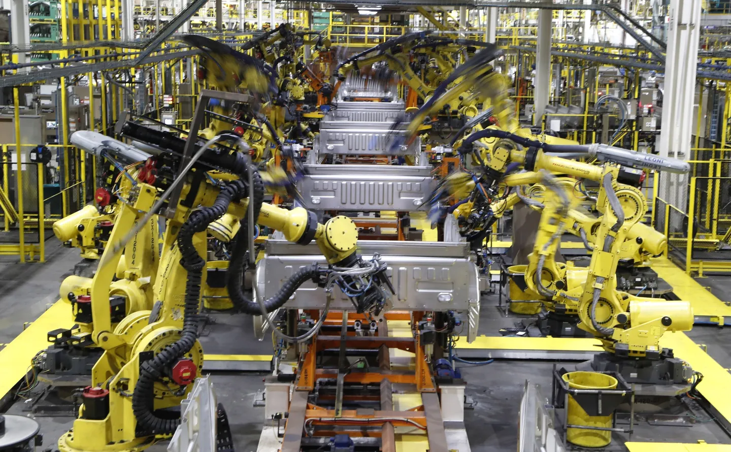 In this Sept. 27, 2018, file photo robots weld the bed of a 2018 Ford F-150 truck on the assembly line at the Ford Rouge assembly plant in Dearborn, Mich. Ford says it wants to reopen five North American assembly plants in April 2020 that were closed due to the threat of coronavirus. The three Detroit automakers suspended production at North American factories March 19 ago under pressure from the United Auto Workers union, which had concerns about members working closely at work stations and possibly spread