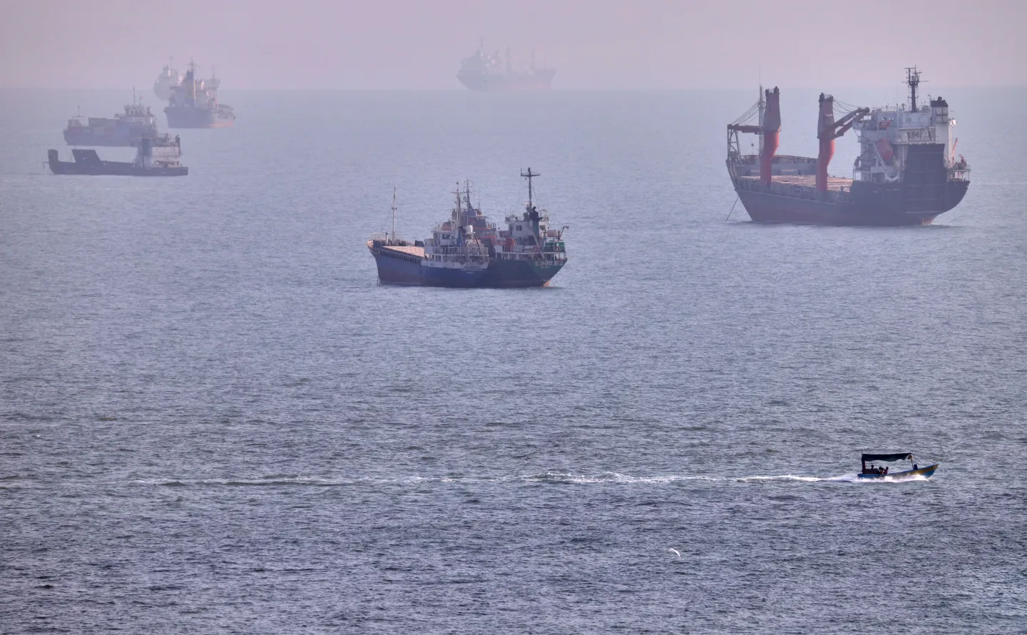 A small boat sails past cargo ships and other commercial vessels anchored in the Strait of Hormuz off Bandar Abbas, Iran, Wednesday, Aug. 5, 2026. (Amirhosein Khorgooi/ISNA via AP)