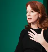Meghan O'Sullivan speaking in front of a green background.