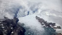 a glacier calves icebergs into a fjord off the Greenland ice sheet
