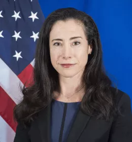Headshot of Mallory Stewart with an American flag over a blue background