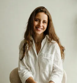 A woman dressed in white sits facing the camera.