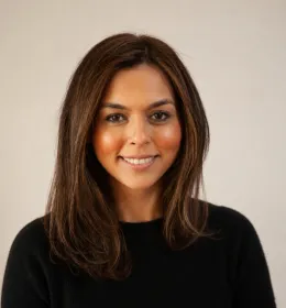 Woman in a black top faces the camera, smiling.
