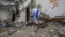 A battle-scarred home draped with an Israeli flag in Kibbutz Be'eri, an Israeli communal farm on the Gaza border. AP Photo/Tsafrir Abayov