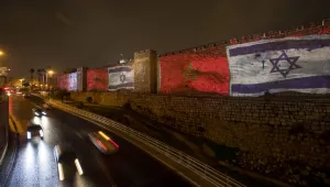Israelis passing by the walls of Jerusalem's Old City next to Jaffa gate lit up with the Israeli and Moroccan flags.