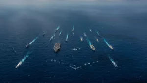 The aircraft carrier USS Ronald Reagan (CVN 76), left, and the Japan Maritime Self-Defense Force helicopter destroyer JS Hyuga (DDH 181), right, sail in formation with 16 other ships from the U.S. Navy and the Japan Maritime Self-Defense Force as aircraft from the U.S. Air Force and Japan Air Self-Defense Force fly overhead in formation during Keen Sword 2019.