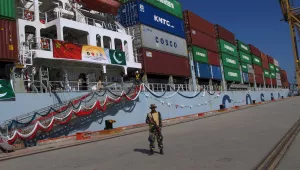 Pakistan Navy soldier stands guard while a loaded Chinese ship prepares to depart.