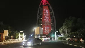 In this Wednesday, July 18, 2018 photo, a sign reading "UAE Chinese Week" in Chinese and Arabic is projected onto the Bus Al Arab luxury hotel to celebrate the UAE Chinese Week in Dubai, United Arab Emirates. Chinese President Xi Jinping is heading to Abu Dhabi in his first trip to the United Arab Emirates as the leader of China as the two countries look to strengthen trade ties and expand investment.