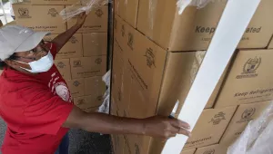 Volunteer Mary Jenkins opens pallet-loads of food to be given out at a food distribution event, Tuesday, Oct. 6, 2020, in Opa-locka, Fla. The drive-thru food distribution was hosted by Feeding South Florida. Shutdowns and restrictions have battered Florida's economy, leaving hundreds of thousands unemployed in the tourist-dependent state. 