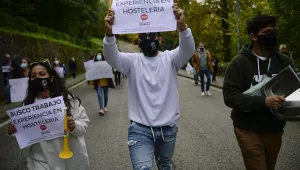 People hold up banners in support of the hotel industry that read: "I search for work", in Pamplona, northern Spain, Wednesday, Oct. 21, 2020, while protesting with others against the new measures against the coronavirus in the Navarra province where all bar and restaurants will be closed for 15 days from midnight Wednesday. 