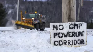A sign that reads "No CMP Powerline Corridor" with mountains and a plow in the background