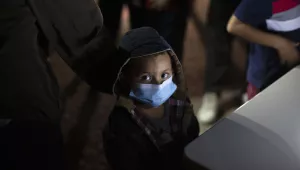 An unaccompanied minor looks up as he waits to answer questions from a U.S. Border Patrol agent at an intake site after he was smuggled on an inflatable raft across the Rio Grande river in Roma, Texas, Wednesday, March 24, 2021. 