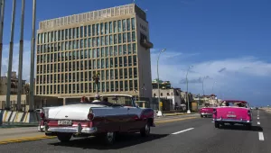 tourists ride classic convertible cars on the Malecon beside the United States Embassy in Havana, Cuba.