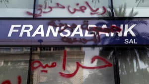 Bank customers write Arabic words thats read "Riad is a thief. Thieves" (Riad Salameh, the governor of Lebanon's Central Bank) on a facade of bank in Beirut, Lebanon, Friday, Nov. 19, 2021. Dozens of Lebanese gathered outside a bank in Beirut's downtown demanding that they be allowed to withdraw their deposits that have been blocked amid Lebanon's severe financial and economic crisis.