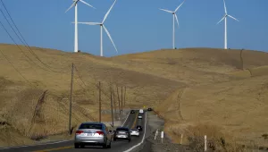 Vehicles move down Altamont Pass Road with wind turbines in the background in Livermore, Calif., on Aug. 10, 2022.