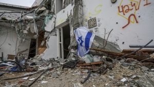 A battle-scarred home draped with an Israeli flag in Kibbutz Be'eri, an Israeli communal farm on the Gaza border. AP Photo/Tsafrir Abayov