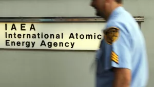 A guard passes the entrance to the International Atomic Energy Agency office in Vienna, Austria (AP Photo/Ronald Zak).