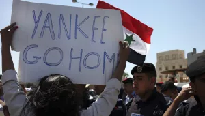 Jordanian security police stand in front of protesters waving the Syrian national flag and holding an anti-American poster during a protest against any American military strike on Syria, near the U.S. embassy, Amman, Jordan, Saturday, Aug. 31, 2013. The United States is considering launching a punitive strike against the regime of Syrian President Bashar Assad, blamed by the U.S. and the Syrian opposition for an Aug. 21 alleged chemical weapons attack in a rebel-held suburb of the Syrian capital of Damascus
