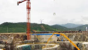 A crane carries a bucket containing concrete to the foundation of a reactor during the first concrete pouring for the Light Water Reactor Project in North Korea on August 7, 2002. 