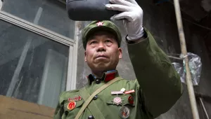In this May 2, 2016 photo, People’s Liberation Army veteran Zhao Shunli uses a rear view mirror to refine his look at his home in Luoyang in central China’s Henan province.