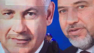 Israeli Foreign Minister Avigdor Lieberman walks under a screen showing him and Israeli Prime Minister Benjamin Netanyahu during the inauguration of their election campaign in Jerusalem, Dec. 25, 2012.