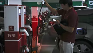 A man prepares to charge his electric-powered vehicle parked at a shopping mall in Beijing, Monday, Sept. 11, 2017. 