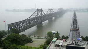 Visitors walk across the Yalu River Broken Bridge, right, next to the Friendship Bridge connecting China and North Korea in Dandong in northeastern China's Liaoning province.