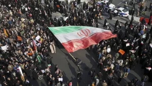 In this photo provided by Tasnim News Agency, a demonstrator waves a huge Iranian flag during a pro-government rally in the northeastern city of Mashhad, Iran, on Jan. 4, 2018 (Nima Najafzadeh/Tasnim News Agency via AP).