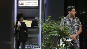 A woman uses ATM outside a bank, as a Lebanese policeman stands guard, in Beirut, Lebanon, Wednesday, Nov. 20, 2019.