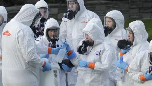 Workers from a Servpro disaster recovery team wearing protective suits and respirators are given supplies as they line up before entering the Life Care Center in Kirkland, Wash., to begin cleaning and disinfecting the facility, Wednesday, March 11, 2020. 