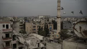 A mosque stands next to a a damaged building, in Idlib, Syria.