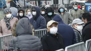 Patients wear personal protective equipment while maintaining social distancing as they wait in line for a COVID-19 test at Elmhurst Hospital Center, Wednesday, March 25, 2020, in New York. 