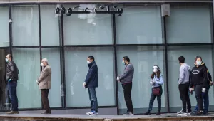 Clients wearing masks to help protect themselves from the coronavirus wait to use ATM machines outside a closed bank in Beirut, Lebanon.