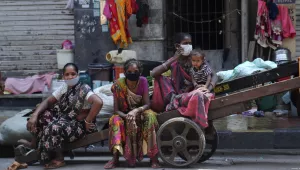 Homeless women wearing masks sit on a hand cart in Mumbai, India, Sunday, March 29, 2020. (AP Photo/Rafiq Maqbool)