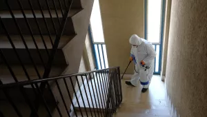 Photo of a man wearing a protective suit sanitizing the stairway of a public housing building to prevent the spreading of the coronavirus, in the neighborhood of Spinaceto, on the outskirts of Rome, Monday, March 30, 2020. 