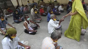 An Indian volunteer distributes clothes and food to impoverished Indians during lockdown to prevent the spread of new coronavirus in Hyderabad, India, Tuesday, April 14, 2020. (AP Photo/Mahesh Kumar A.)