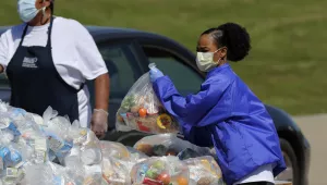 T.W. Browne Middle School food service employees Shannon Wiggins, left, and Katrina Parker, right, distribute food to a Dallas Independent School District family in Dallas, Thursday, April 16, 2020. 