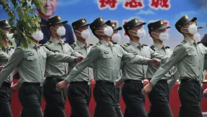 Photo of Chinese People's Liberation Army (PLA) soldiers wearing face masks to protect against the spread of the new coronavirus march past a banner depicting Chinese President Xi Jinping at their living squatter inside the Tiananmen Gate in Beijing during a plenary session of China's National People's Congress (NPC) at the Great Hall of the People in Beijing, Monday, May 25, 2020. 
