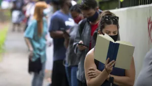 Photo of Kelsey Luker reading as she waits in line to vote, Tuesday, June 9, 2020, in Atlanta. Luker said she had been in line for almost two hours. 