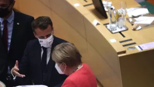 French President Emmanuel Macron, second right, looks over papers with German Chancellor Angela Merkel, right, during a round table meeting at an EU summit in Brussels, Monday, July 20, 2020. 