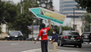 John Miller, 25, of Atlanta, spins a large check sign for the #OneCheckIsNotEnough campaign near Georgia Sen. David Perdue's office on Tuesday, Aug. 11, 2020, in Atlanta. 