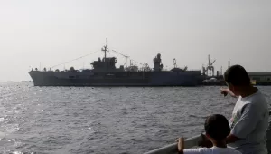 A man and his son look out across the sea at the USS Blue Ridge, the command ship of the U.S. Seventh Fleet, March 18, 2014.